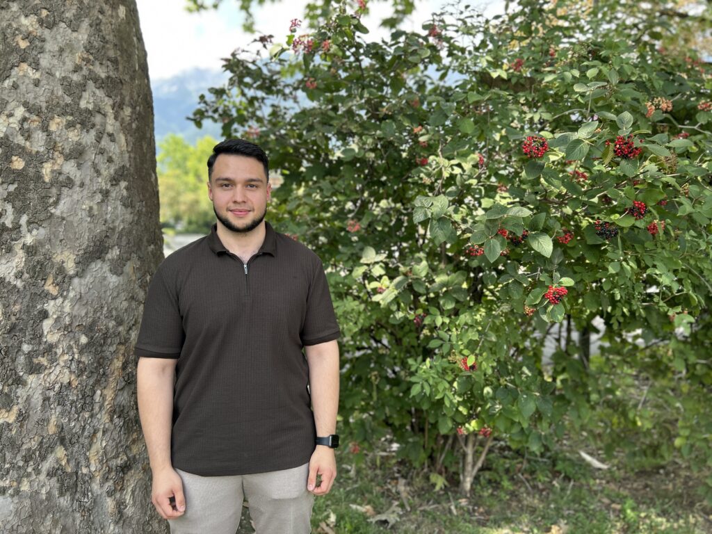 Portratbild Emirhan Tuna vor Baumkulisse