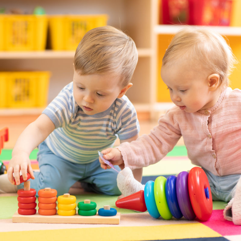 "Preschool boy and girl playing on floor with educational toys. Children at home or daycare."