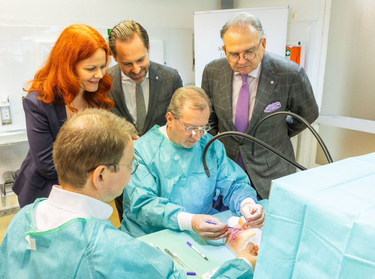 LRin Cornelia Hagele, Direktor Marko Konschake und Rektor Wolfgang Fleischhacker (hintere Reihe, von li.) schauen den Klinikdirektoren Matus Rehak und Anton Schwabegger (vorne, von re.) bei einer Tumor-OP am 3D-Augenlid über die Schultern.